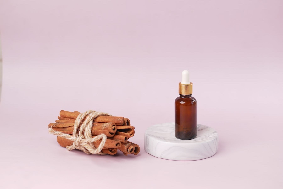 Olejek w szklanej buteleczce, obok laski cynamonu