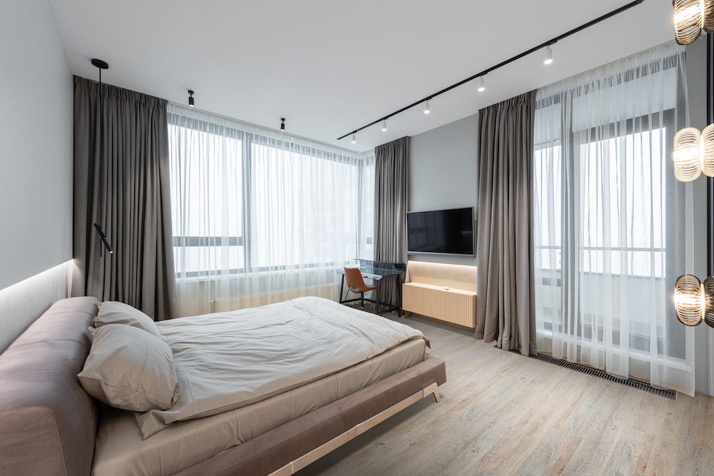 Sypialnia z panelami winylowymi, łóżkiem i dużymi oknami