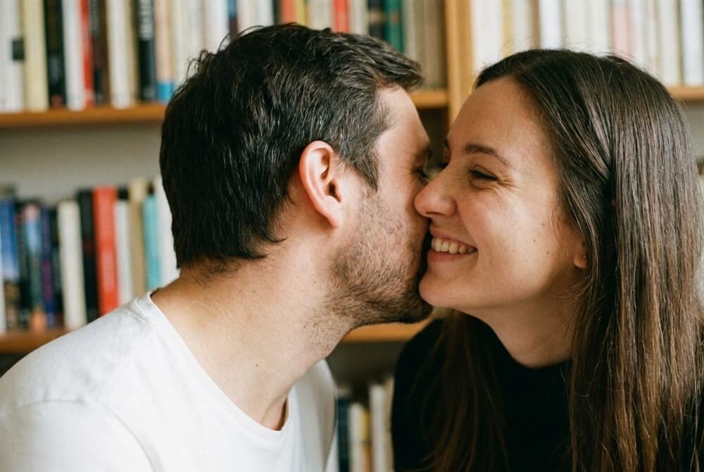 Para wykonuje towarzyski „pocałunek europejski” policzek w policzek, dyskretna serdeczność