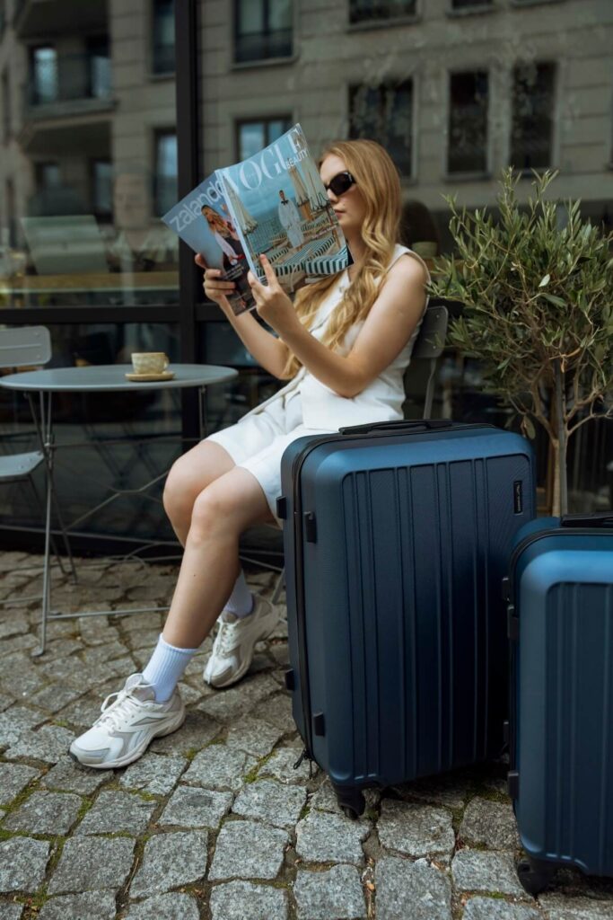 Kobieta z walizkami czytająca Vogue