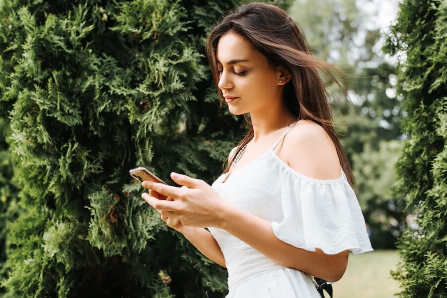 Zaintrygowana dziewczyna czytająca wiadomość SMS podczas spaceru