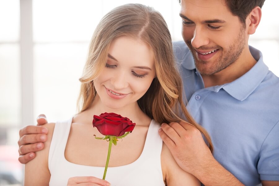 Kobieta z pojedynczym kwiatem róży przy mężczyźnie