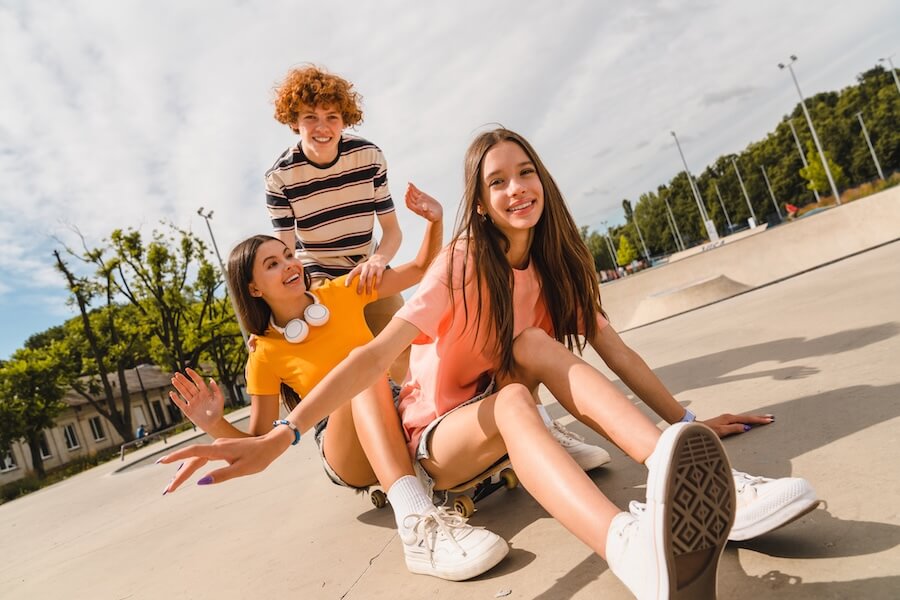 Grupka znajomych, młodzież bawiąca się podczas jazdy na deskorolce