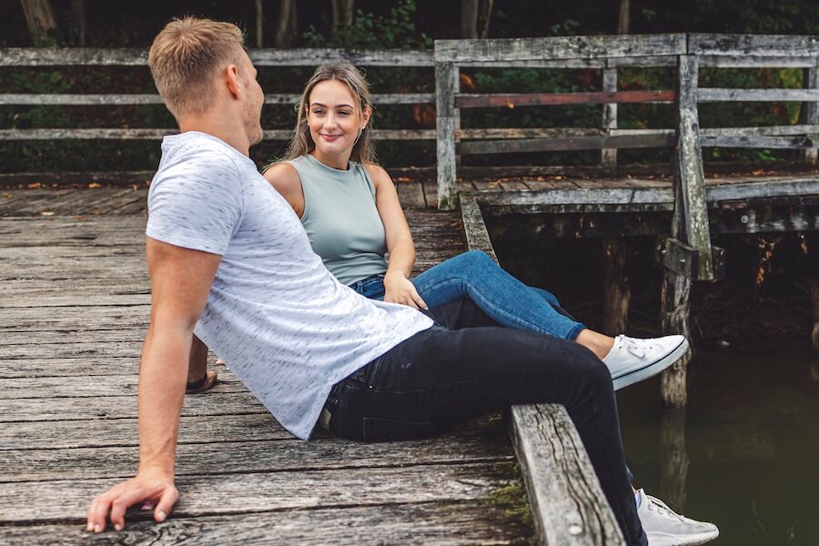 Sympatyczna rozmowa chłopaka z dziewczyną na pomoście przy jeziorze