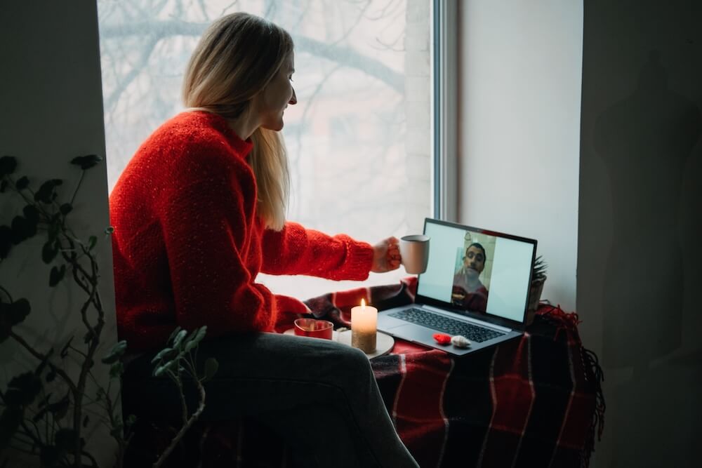 Kobieta w czerwonym sweterku rozmawiająca na kamerce wideo online z partnerem