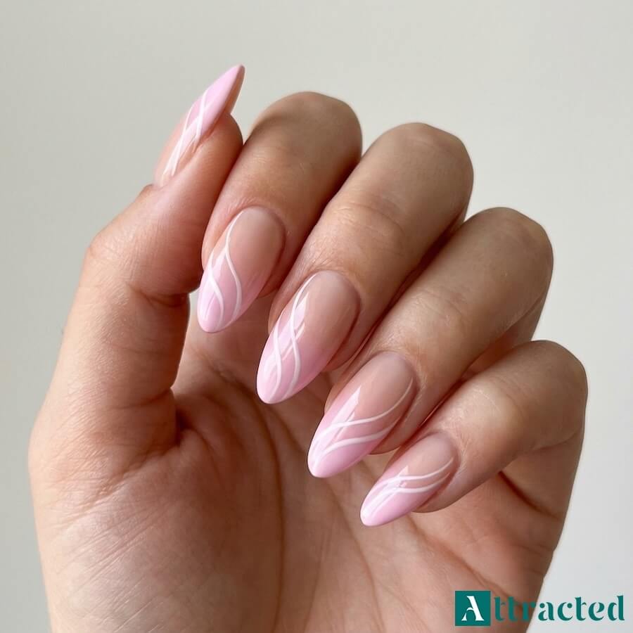 Zbliżenie jednej dłoni z migdałkowymi paznokciami ombre french nude do pastelowego różu z białymi zawijasami, na jasnym neutralnym tle