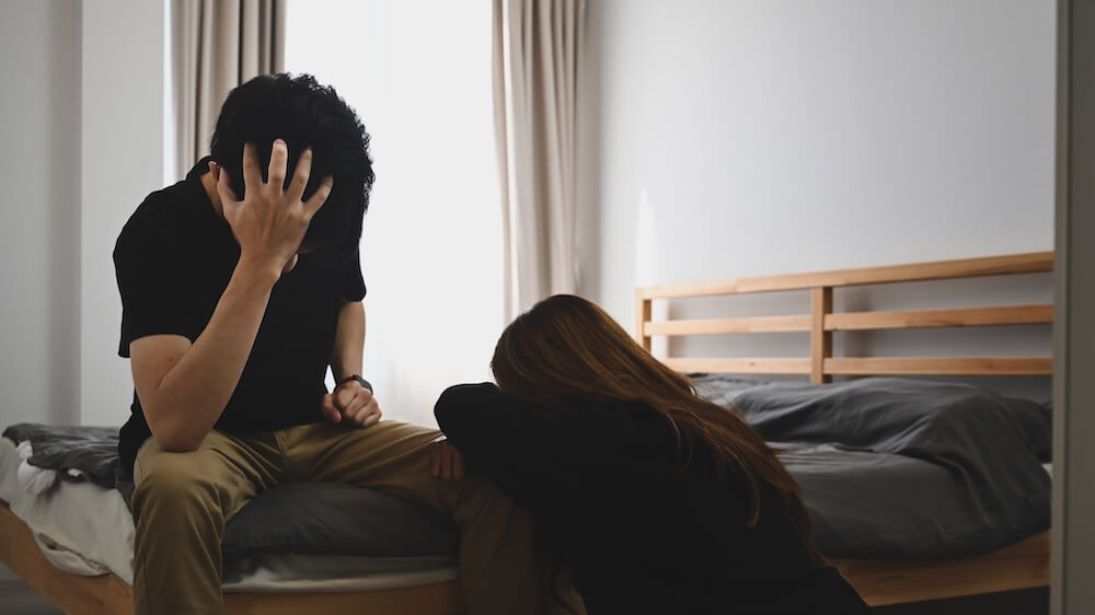 Załamana para, chłopak i dziewczyna pogrążeni w żalu przy łóżku w pokoju