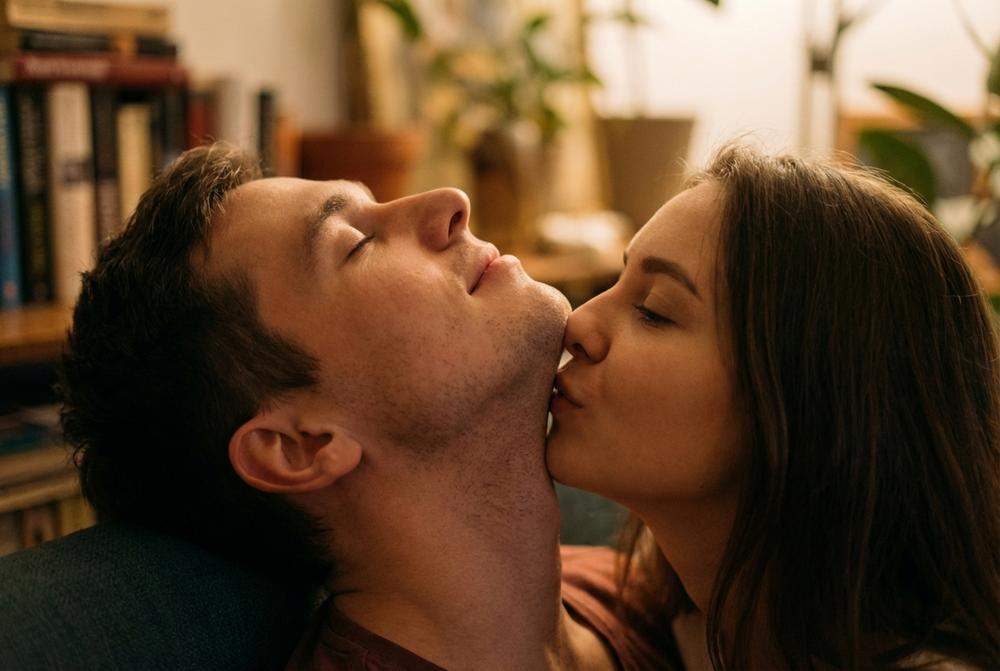 Kobieta całująca mężczyznę w szyję i linię szczęki