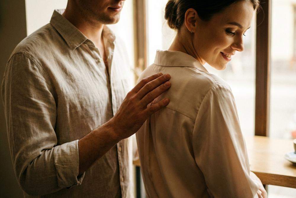 mężczyzna trzyma dłoń na plecach kobiety w kawiarni