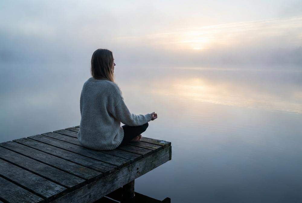 Kobieta medytująca nad jeziorem separacja
