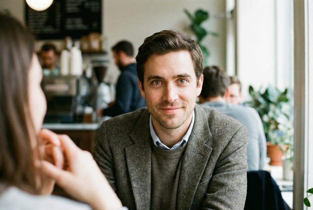 Mężczyzna w kawiarni utrzymujący intensywny kontakt wzrokowy i uśmiechający się