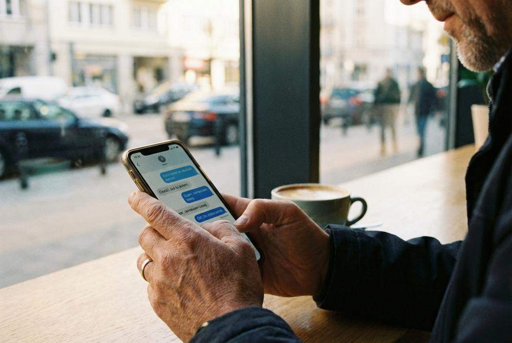 Mężczyzna piszący wiadomość na smartfonie w kawiarni