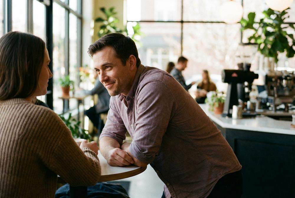 Mężczyzna pochyla się w stronę kobiety podczas randki w kawiarni