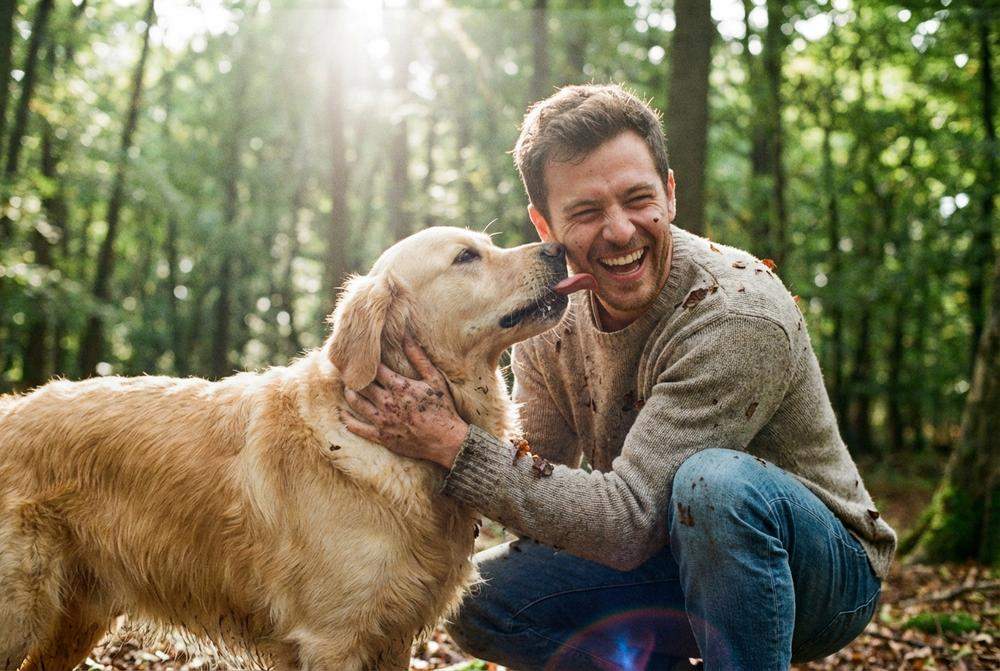 Szczęśliwy mężczyzna bawiący się z psem w parku