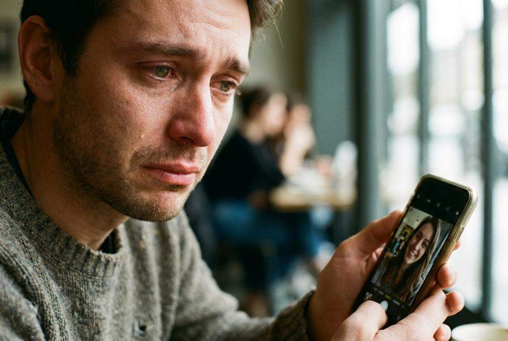 mężczyzna tęskniący ogląda telefon