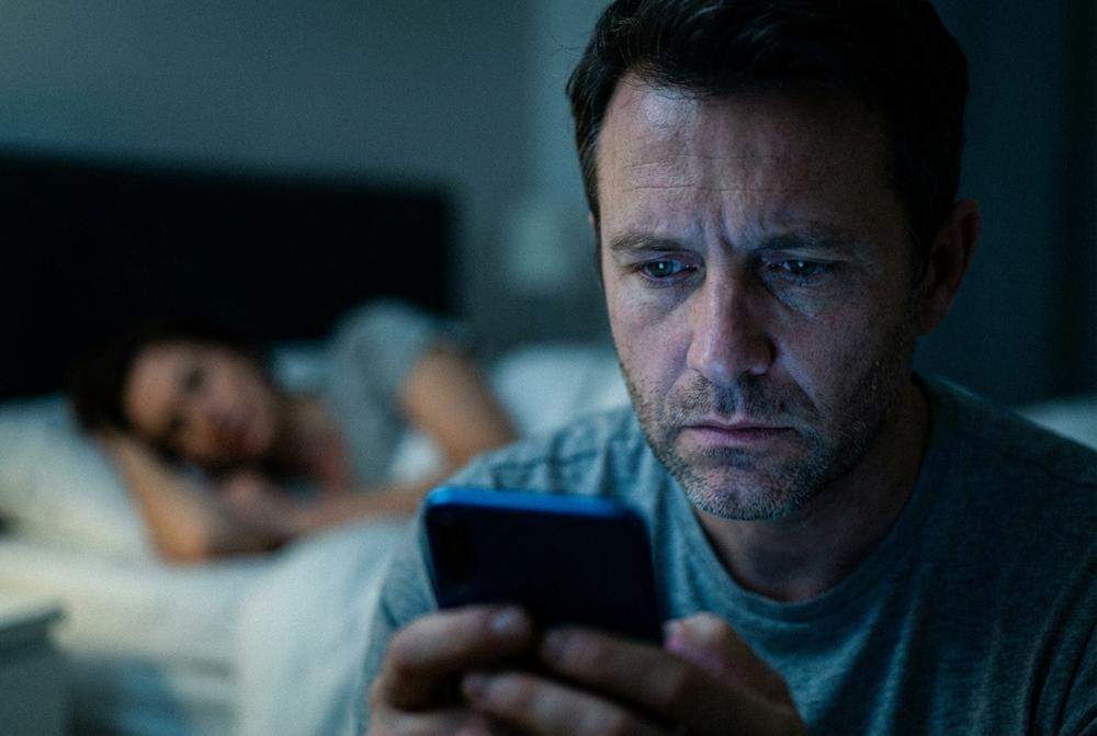 Zamyślony żonaty mężczyzna w nocy z telefonem